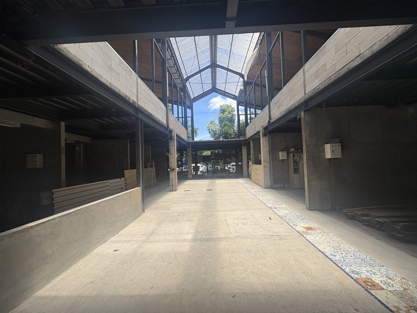 KORA main alley — glass roof structure, units on both sides, decorative tile floor